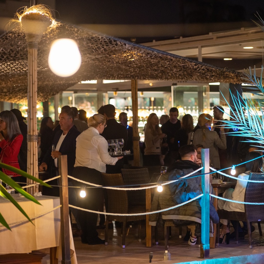 Terraza de cena de SOHO Fire & Grill de noche, con la brasa al fondo